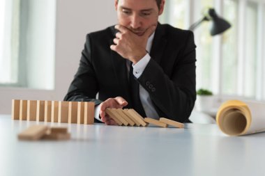 Onun şirketin geleceği planları gibi domino etkisi eliyle durdurma masasında oturan endişe ciddi iş adamı.