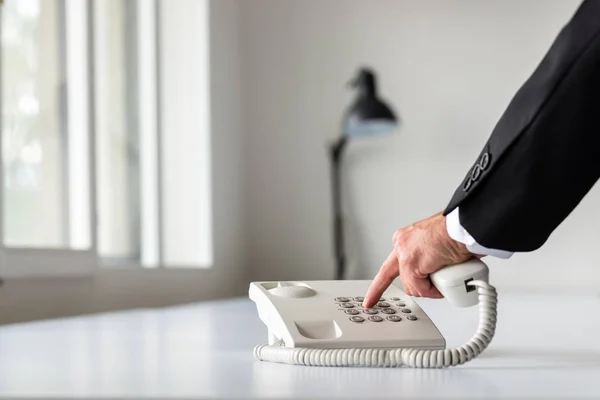 商人在白色办公桌上使用白色固定电话亲手拨打电话号码 — 图库照片