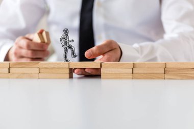 İş takım çalışması ve işbirliği kavramı - ahşap mandal erkek el tarafından desteklenen bir işadamı bir köprüden diğer tarafa yürümeye silüeti yapılmış.