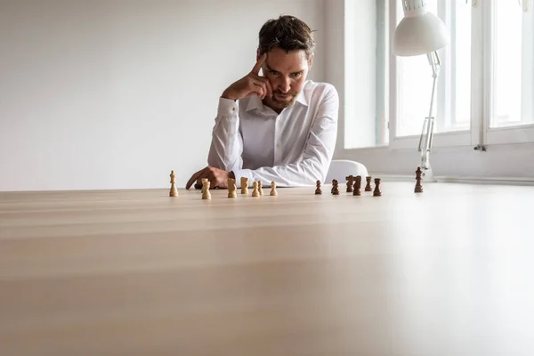 若いビジネス経営者 リーダーの人事意思ヒス事務所机の上の部分を黒と白のチェスのチームとの彼の机でやま — ストック写真