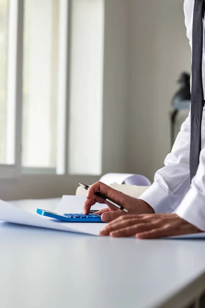 Empresário Inclinado Sua Mesa Escritório Usando Calculadora Como Ele Analisa — Fotografia de Stock