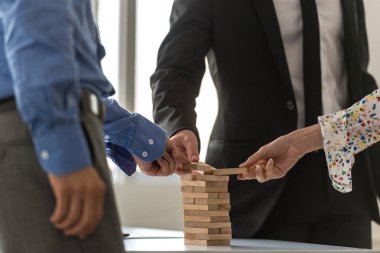 Ahşap mandal kavramsal bir görüntüde bir kule inşa için birlikte çalışan üç iş adamları iş ekibi.