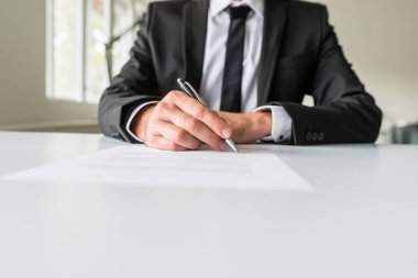 İşadamı veya işveren sözleşme ya da çalışma kağıt kalemle imzalama onun ofis masasında oturan önden görünümü.