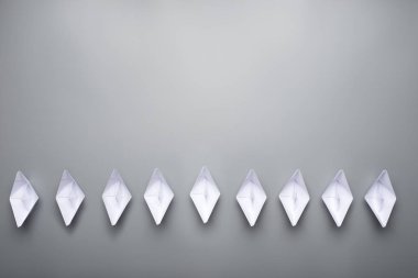Üstten görünüm dokuz kağıt origami tekneler alt kısmındaki görüntü üzerinde kopya alanı bol olan gri arka plan üzerinde yapılan.