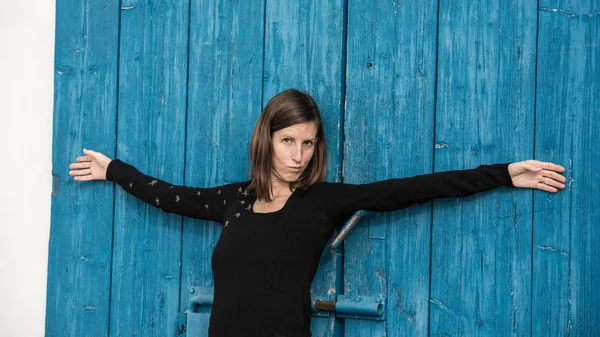 Young Woman Leaning Blue Rustic Wooden Door Her Arms Wide — Stock Photo, Image