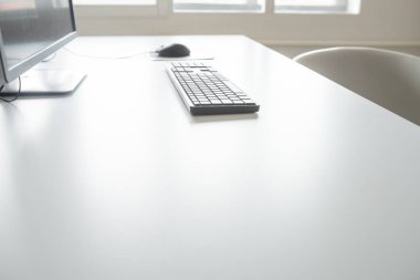 Beyaz ofis masasında office bilgisayar - monitör, fare ve klavye, düşük açılı görünüş.
