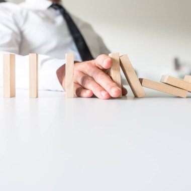 Onun yerleştirerek işadamı dominos düşen durdurmak için el ve kavramsal bir görüntü krizde önlemek.