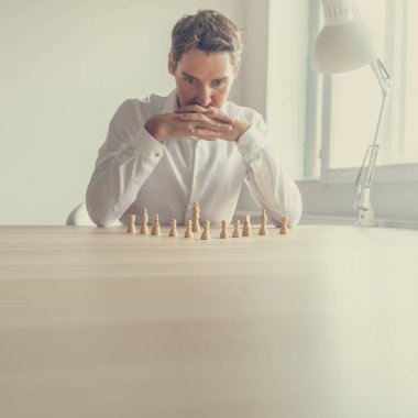 İş işveren o Ofis Masası üzerinde konumlandırılmış satranç taşları olduğu gibi en iyi stratejik hareket kavramsal bir görüntüde yapmak için beyin fırtınası.