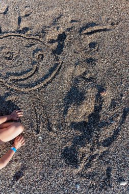 Bir çocuğun bir kumsalda bir kum mutlu gülen yüz çizim Üstten Görünüm.