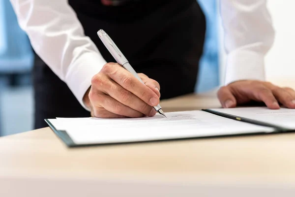 Geschäftsmann Steht Seinem Schreibtisch Und Unterschreibt Einen Bericht Oder Vertrag — Stockfoto