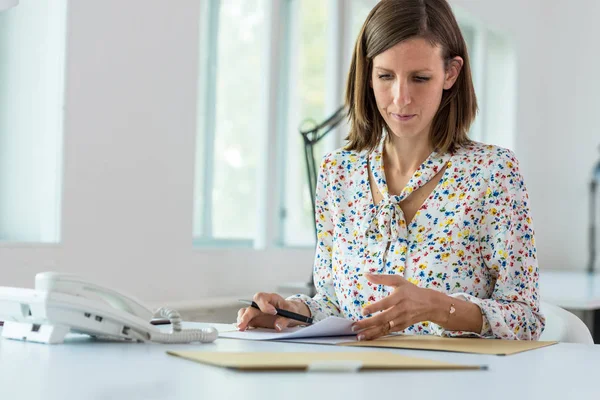 Ung affärskvinna sitter vid hennes office desk arbetar — Stockfoto