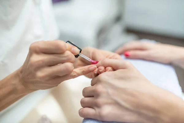 Nahaufnahme von Maniküre, die glänzend roten Nagellack aufträgt — Stockfoto