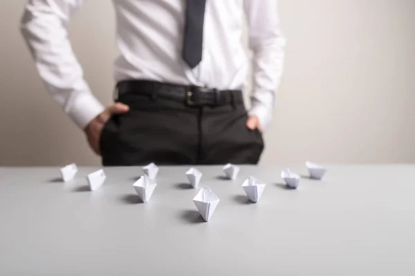 Homme d'affaires debout derrière un bureau avec des bateaux en papier origami — Photo