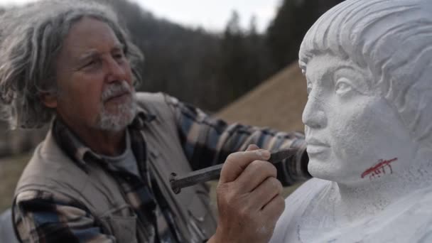 Senior sculpting in a stone with chisel — Stock Video