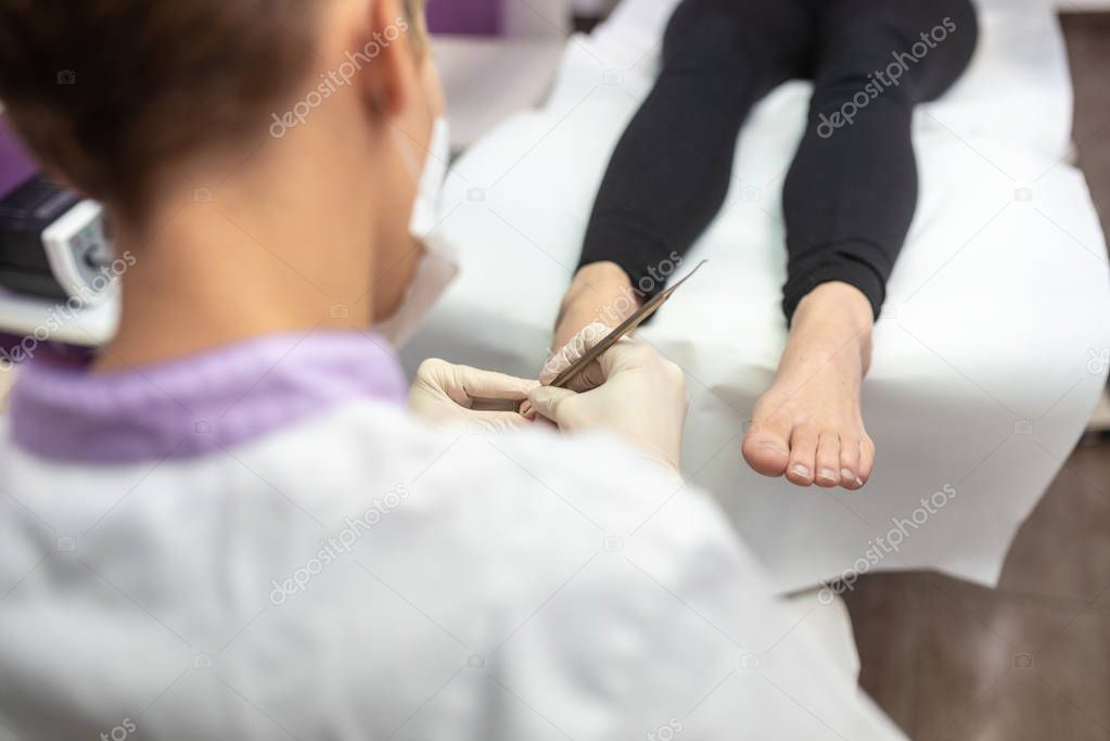 Over the shoulder view of podiatrist removing cuticle