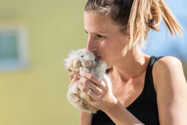 Mujer joven besando a su conejito mascota — Foto de Stock