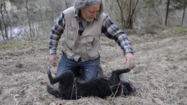 Siyah köpeğiyle oynayan nehir kıyısında katta oturan üst düzey adam