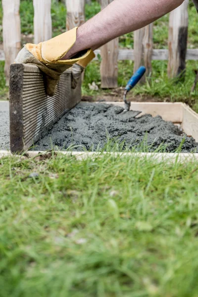 Man wearing protective work gloves leveling fresh cement — Stock Photo, Image