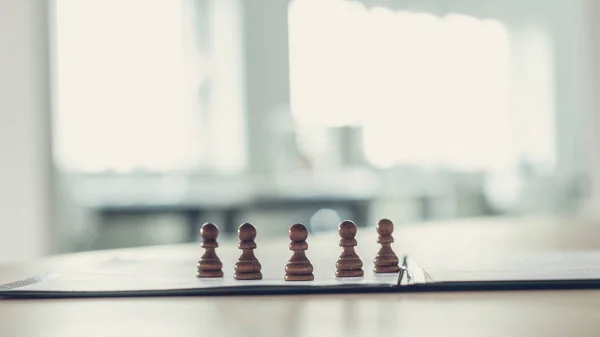 Cinco figuras de ajedrez de peón de pie en un formulario de solicitud o docum —  Fotos de Stock