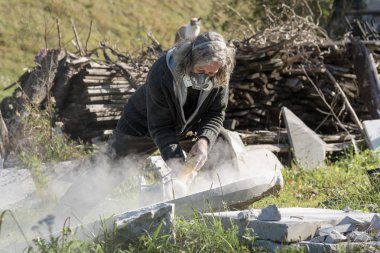 Koruyucu maskeyle dışında çalışan bir heykeltraş 