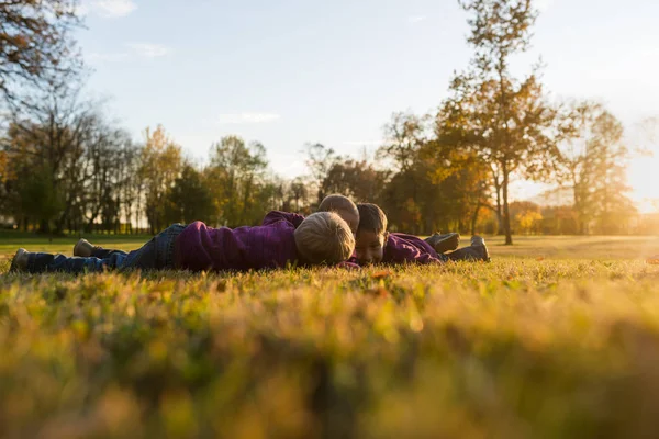 Tiga anak kecil, saudara kandung, berbaring di rumput musim gugur — Stok Foto