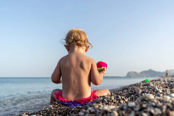 Lilla barn girl i rosa baddräkt som sitter på vackra pe — Stockfoto