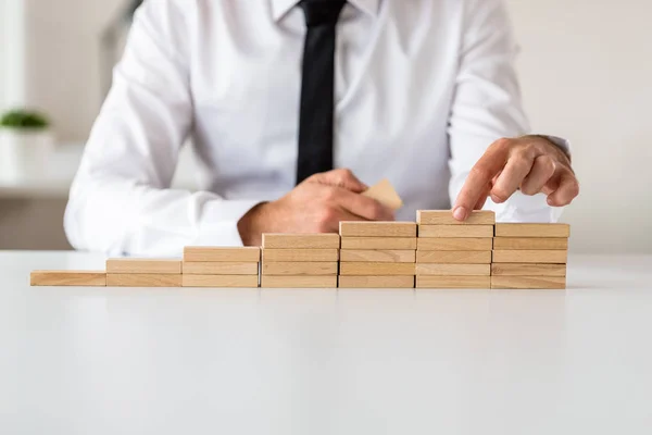 Homme d'affaires faisant des escaliers de chevilles en bois dans une image conceptuelle — Photo