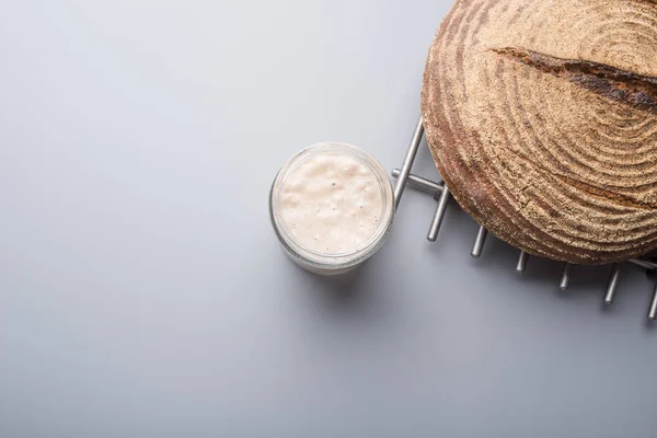 Top view of sourdough starter yeast in a glass jar and bread