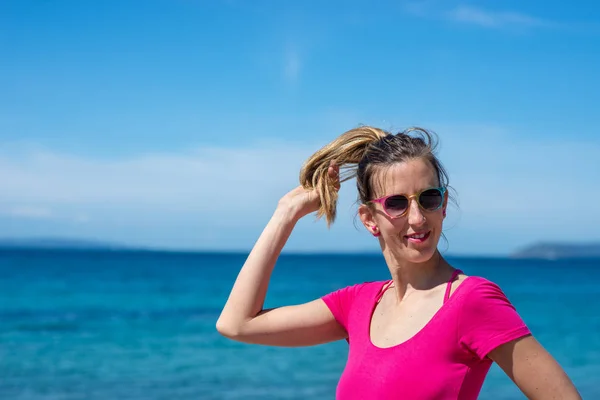 Jovem mulher de camisa rosa desfrutando de férias à beira-mar — Fotografia de Stock