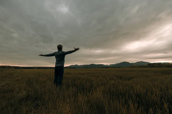 Jovem de pé no prado sob o céu trovão — Fotografia de Stock