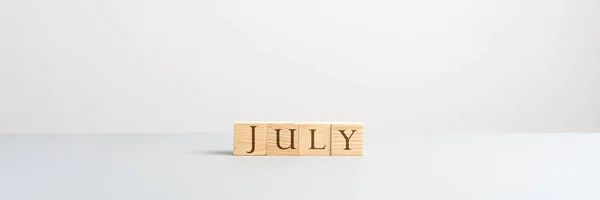 七月拼写与木立方体 — 图库照片