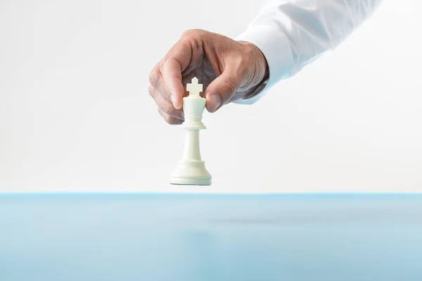 Empresario a punto de colocar una figura de ajedrez rey en un azul —  Fotos de Stock
