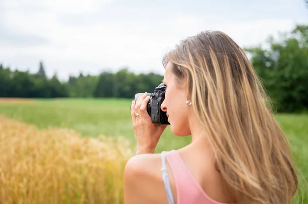 Giovane fotografa donna che scatta una foto di campi in natura — Foto Stock