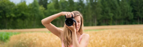 Imagem ampla vista de uma jovem fotógrafa tirando uma foto — Fotografia de Stock