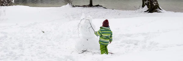 Toddler child making snowman — Stock Photo, Image
