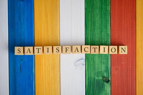 Wooden cubes in a row spelling the word Satisfaction — Stock Photo, Image