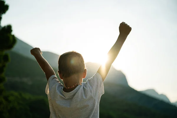 Маленький ребенок с руками в воздухе, приветствуя восходящее солнце — стоковое фото
