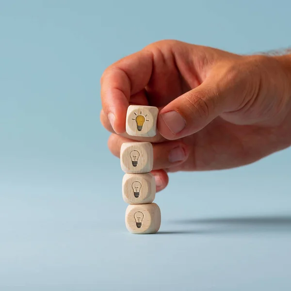 Hand stacking dices with light bulb symbol on them — Stock Photo, Image