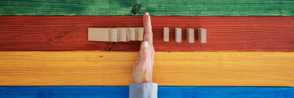 Mano maschile che interviene per impedire al domino di collassare — Foto Stock