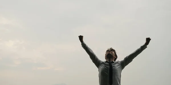 Бізнесмен стоїть під небом з піднятими руками — стокове фото