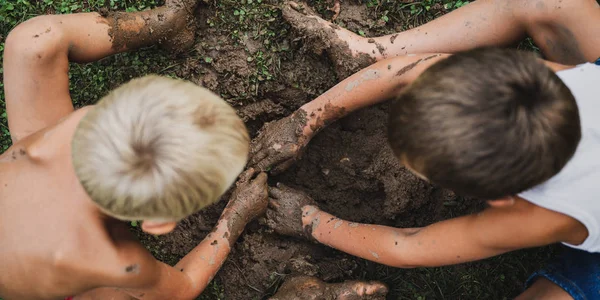 Peuter jongens graven een modderige gat — Stockfoto