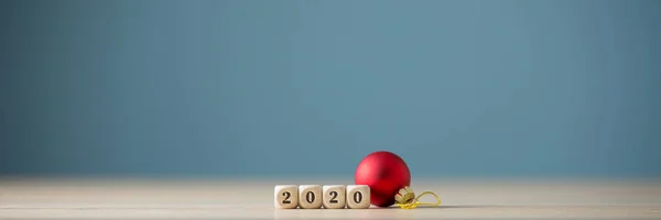 2020 sign on wooden dices with simple red holiday bauble next to — Stock Photo, Image