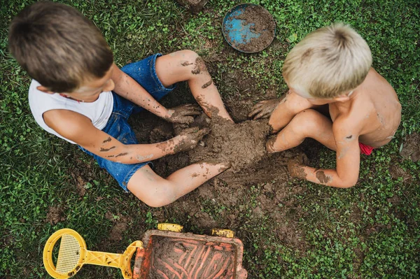 Saudara Toddler duduk di rumput bersenang-senang bermain dengan lumpur — Stok Foto