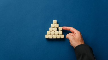 İşletme yöneticisi ahşap zarlarla bir piramit inşa ediyor.