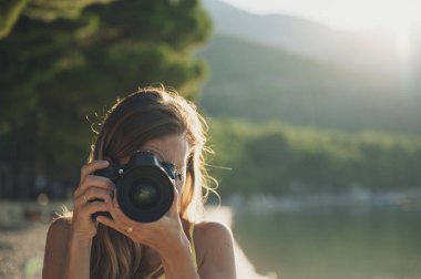 Genç bir kadın doğrudan kameraya fotoğraf çekiyor.