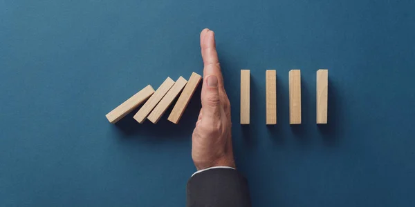 Business crisis manager stopping falling dominos from collapsing — Stock Photo, Image