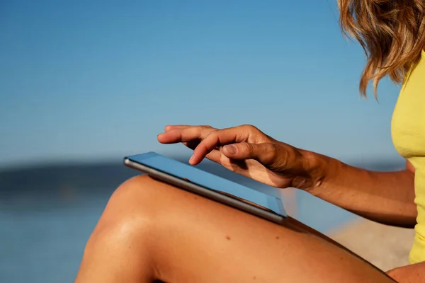Nő ül a tengerparton böngészi a digitális táblagép — Stock Fotó