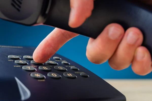 Mužská ruka držící telefonní sluchátko vytáčí telefonní číslo — Stock fotografie