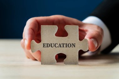 Üzerinde eğitim işareti olan bir yapboz parçasını tutmak.