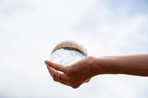 Sfera di cristallo di tenuta della mano femminile con campo che riflette in esso — Foto Stock